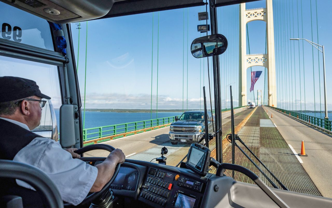 man driving bus on bridge